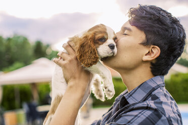 Side view of young man kissing dog in yard - MASF04756