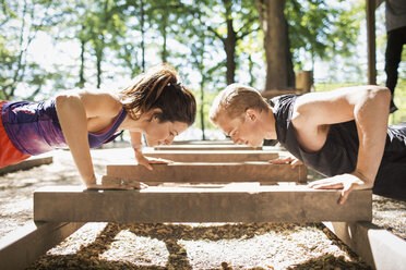 Seitenansicht eines Paares bei Liegestützen in einem Fitnessstudio im Freien - MASF04757