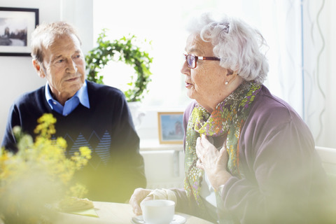 Ältere Frau im Gespräch mit Freunden am Frühstückstisch im Pflegeheim, lizenzfreies Stockfoto