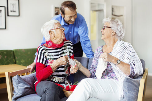Ältere Frau spricht mit Mann beim Stricken im Pflegeheim - MASF04767