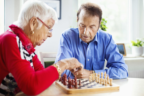 Älteres Paar spielt Schach am Tisch im Pflegeheim, lizenzfreies Stockfoto