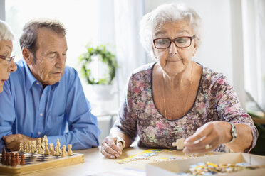 Ältere Menschen spielen Freizeitspiele am Tisch im Pflegeheim - MASF04769