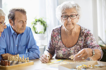 Senior people playing leisure games at table in nursing home - MASF04769