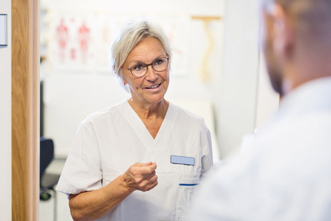 Oberarzt im Gespräch mit einem Mann in einer orthopädischen Klinik, lizenzfreies Stockfoto