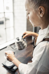 Side view of barista pouring boiling water in coffee filter - MASF04794