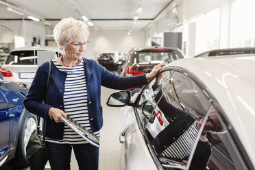 Senior woman admiring car in dealership store - MASF04797