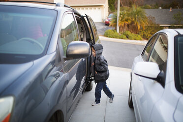 Side view of boy entering car on street - CAVF41663