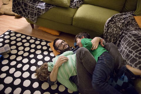 High angle view of children lying on father in living room stock photo