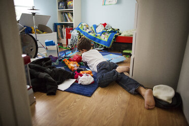 Rückansicht eines Jungen, der mit Spielzeug spielt, während er im Schlafzimmer liegt - CAVF41668