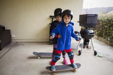 Mädchen, das einem Jungen hilft, auf einem Skateboard im Hof zu stehen - CAVF41671