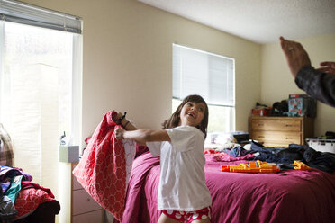 Cheerful girl throwing pillow in bedroom - CAVF41685