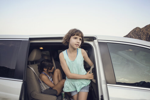 Mädchen schaut weg, während sie auf einer Autotür steht - CAVF41722