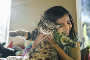 Happy girl with cat on bed at home - CAVF41757