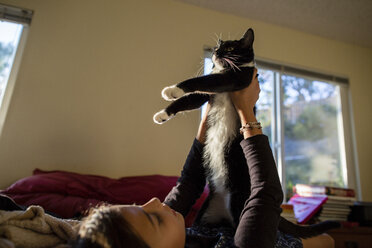 Mädchen spielt mit Katze beim Entspannen auf dem Bett zu Hause - CAVF41764