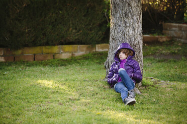 Thoughtful girl relaxing on grassy field by tree in park - CAVF41801
