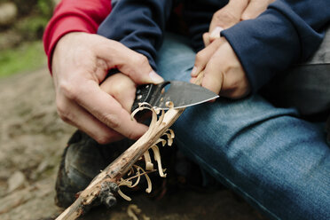 Midsection of father assisting son in cutting wood at Newbury Park - CAVF41809