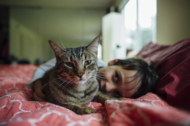 Portrait of cat by boy on bed at home - CAVF41813
