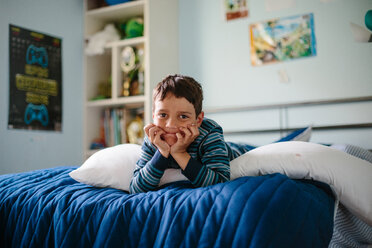 Portrait of boy lying on bed at home - CAVF41842