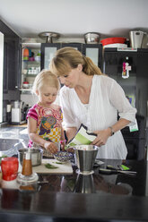 Mutter und Tochter bereiten Essen in der Küche vor - MASF04824