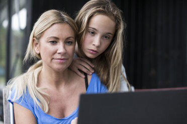 Mutter und Tochter benutzen Laptop auf dem Hof - MASF04829