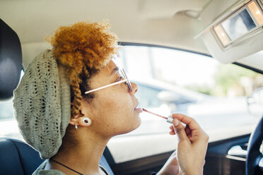 Woman applying lip gloss while sitting in car - CAVF41901