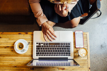 Overhead view of woman using laptop computer while sitting at restaurant - CAVF41903