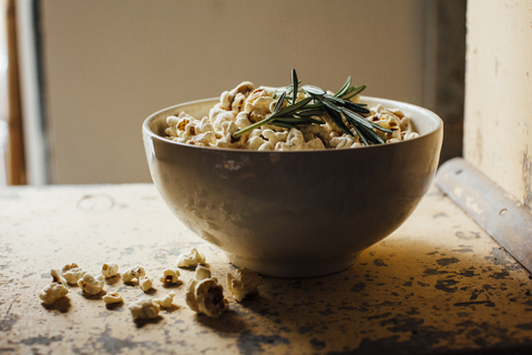 Schale mit Popcorn und Rosmarin auf dem Tisch, lizenzfreies Stockfoto