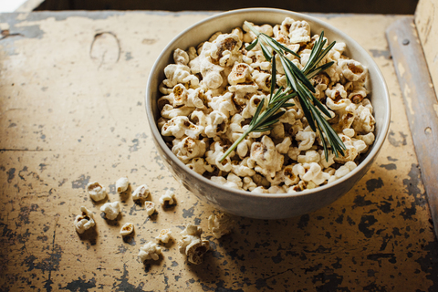 Hohe Winkelansicht von Popcorn und Rosmarin in einer Schüssel auf dem Tisch, lizenzfreies Stockfoto