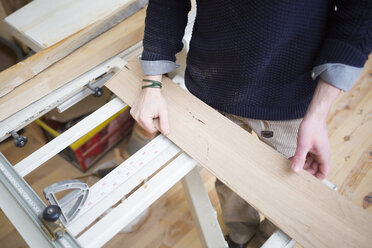 Low section of carpenter measuring wooden planks at workshop - CAVF41929