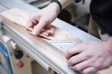 Abgeschnittene Hände eines Zimmermanns, der in der Werkstatt Holzbretter ausmisst - CAVF41933