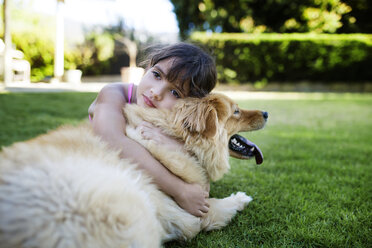 Girl resting with dog in yard - CAVF41972