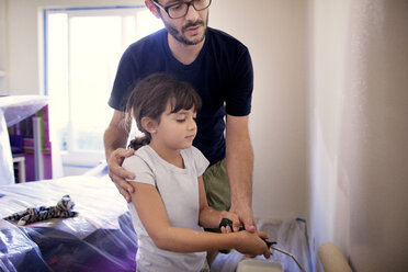 Father assisting daughter in painting wall at home - CAVF41978