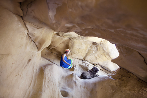 Niedriger Blickwinkel von Mädchen und Hund auf einem Felsen sitzend, lizenzfreies Stockfoto