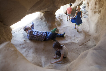 Vater entspannt sich, während Kinder in einer Höhle spielen - CAVF41991