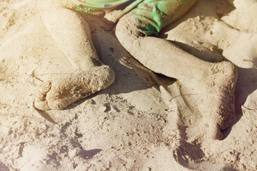 Messy legs on boy lying on sand at beach - CAVF41994