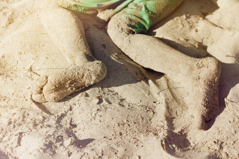 Unordentliche Beine eines Jungen, der am Strand im Sand liegt - CAVF41994