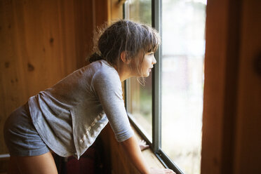 Seitenansicht eines Mädchens, das durch ein Fenster hinausschaut - CAVF42004