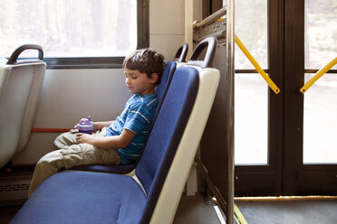 Boy sitting on seat while travelling in train - CAVF42023