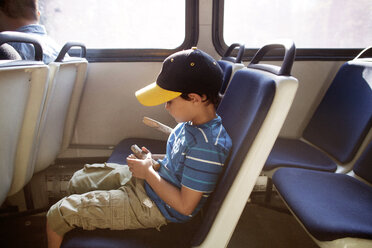 Boy holding wood and sitting on seat while travelling in train - CAVF42034