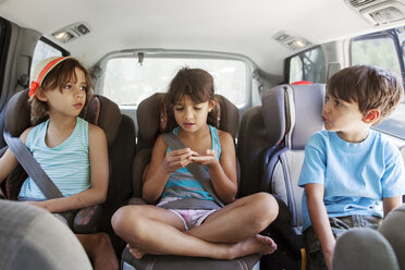 Front view of siblings sitting in car - CAVF42039