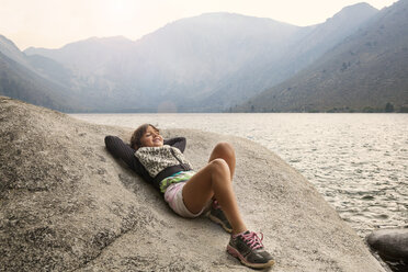 Glückliches Mädchen entspannt sich auf einem Felsen mit Blick auf den Convict Lake und die Berge - CAVF42047