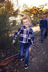 Porträt eines glücklichen Jungen, der mit seinen Brüdern auf einem Feld spazieren geht - CAVF42081