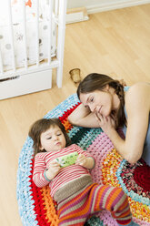 High angle view of woman looking at girl using mobile phone on floor at home - MASF04886