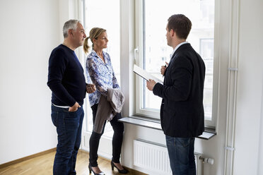 Male real estate agent discussing with couple at home - MASF04893