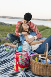 Man kissing girlfriend during picnic on field - MASF04905