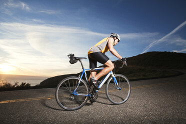 Side view of cyclist riding bicycle on road against sky - CAVF42162