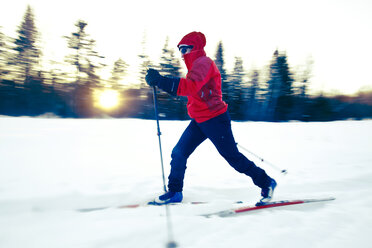 Full length of skiier skiing on snow covered field by bare trees - CAVF42218