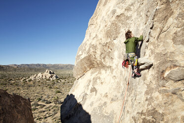 Mann klettert Felsformation gegen klaren Himmel an einem sonnigen Tag - CAVF42220