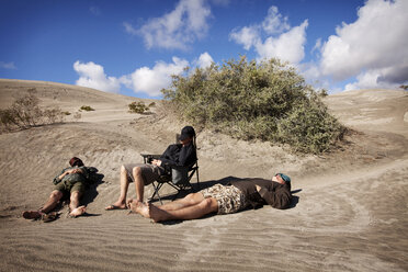 Freunde entspannen sich am Sandstrand gegen den Himmel an einem sonnigen Tag - CAVF42266