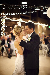 Braut und Bräutigam tanzen in beleuchtetem Raum während der Hochzeit - CAVF42272